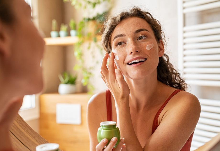 woman applying skincare in mirror